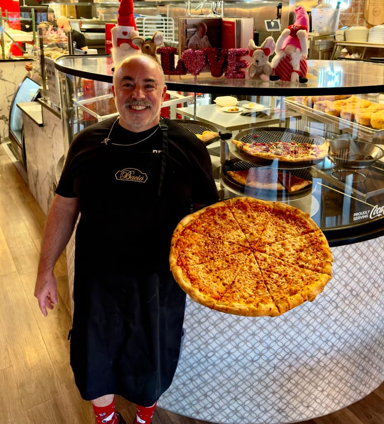 Owner of Antonio's Real New York Pizza holding a large New York-style cheese pizza